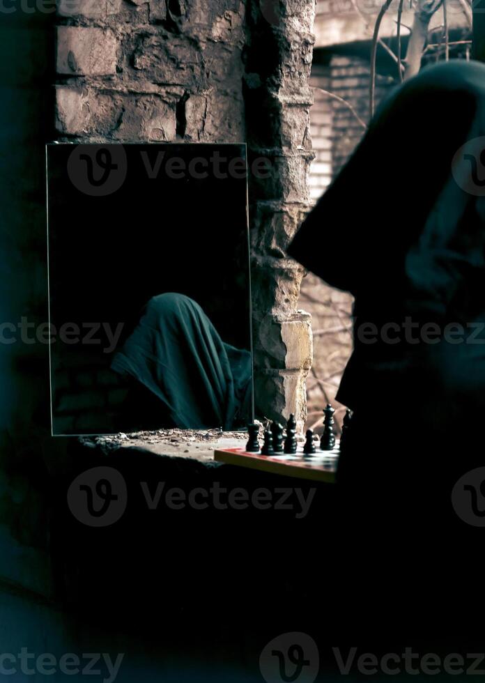 Mysterious Hooded Figure Reflected In Mirror Beside A Chessboard In Abandoned Room, Dim Lighting. photo
