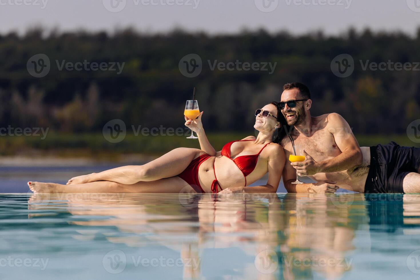 Couple relaxing by the pool with drinks photo