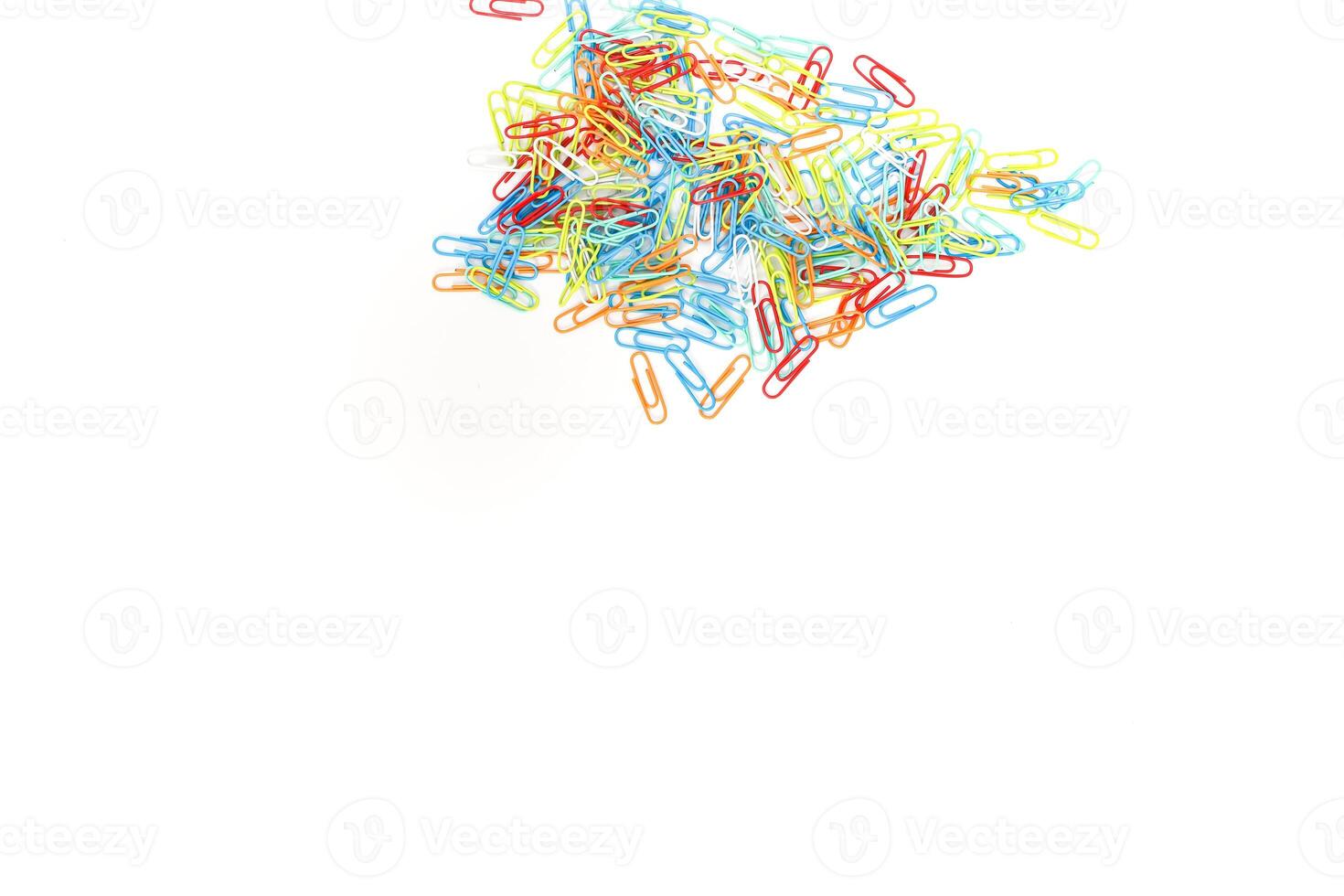 A vibrant cluster of colorful paper clips scattered on a clean, white background, creating a visually appealing stationery scene photo