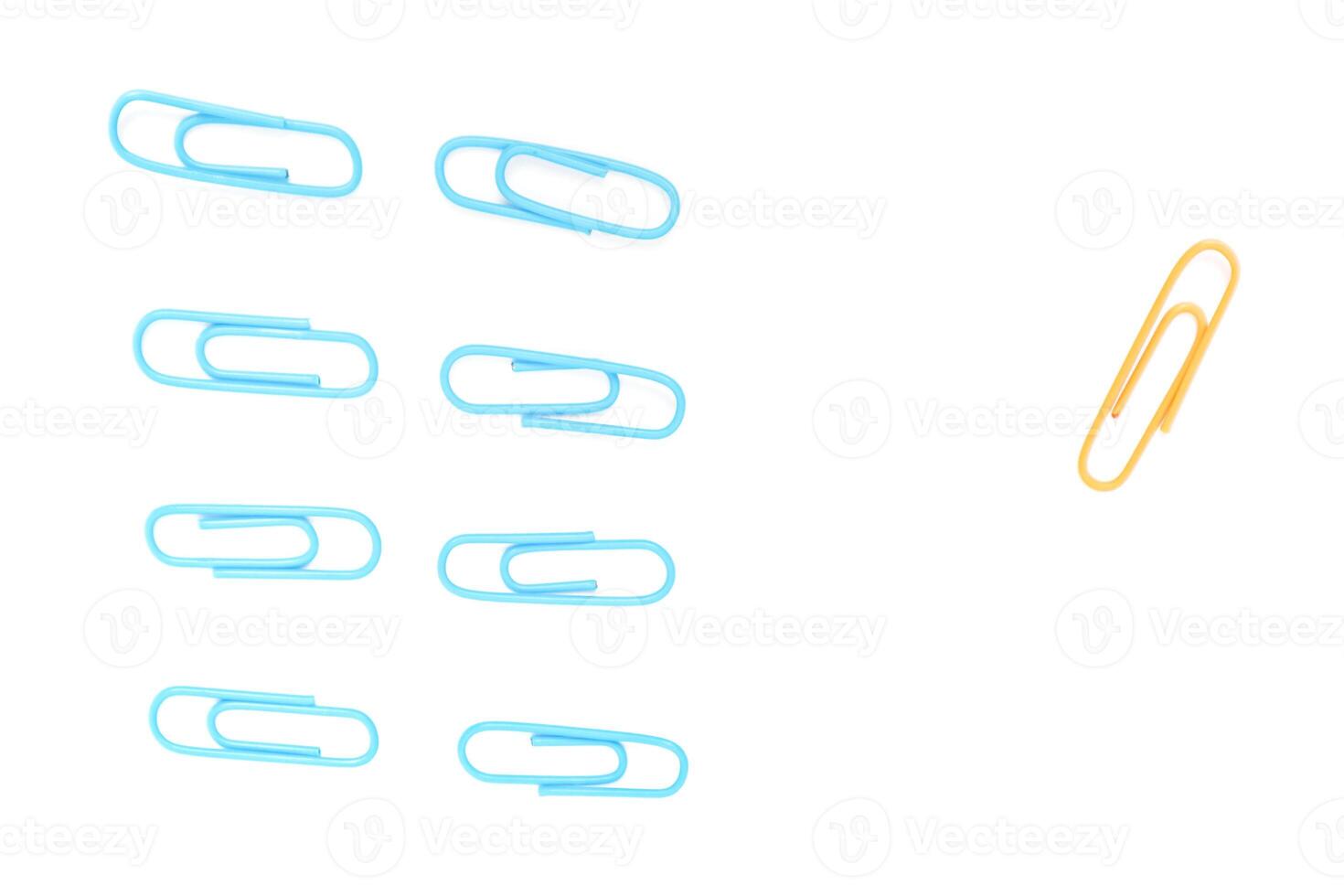 A Conceptual Image of Blue Paper Clips Grouped Apart from a Single Yellow One on White photo