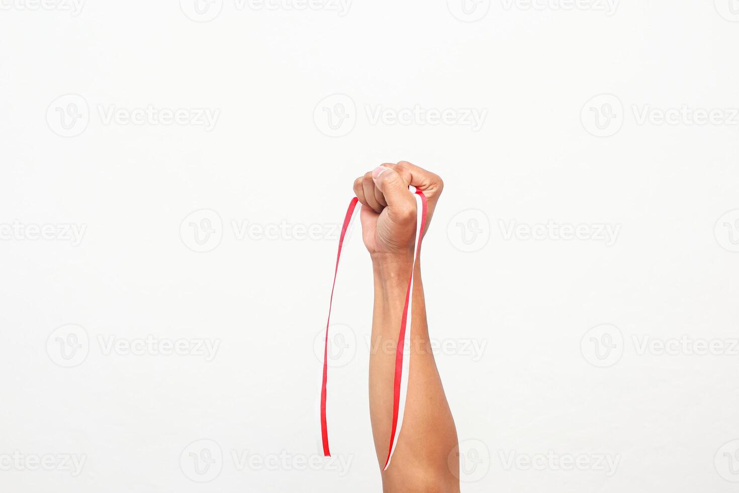 Raised Fist Holding Indonesian Flag Ribbon Symbolizing Independence Day Celebration photo