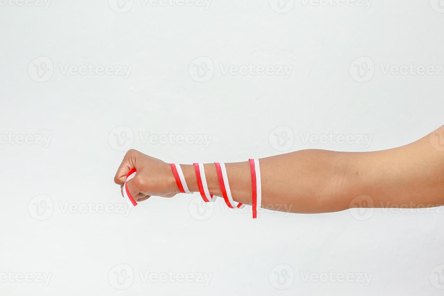 Arm wrapped in red and white ribbons against a plain background creating minimalist visual photo