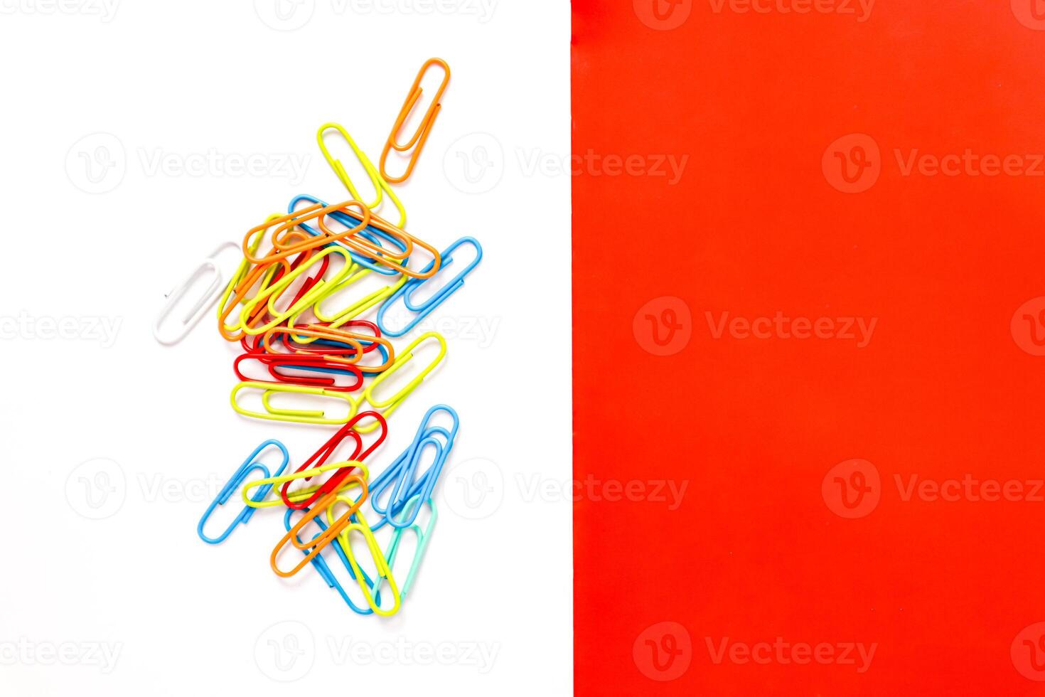 Vibrant Colored Paper Clips Scattered on White Background with Red Accent Section photo