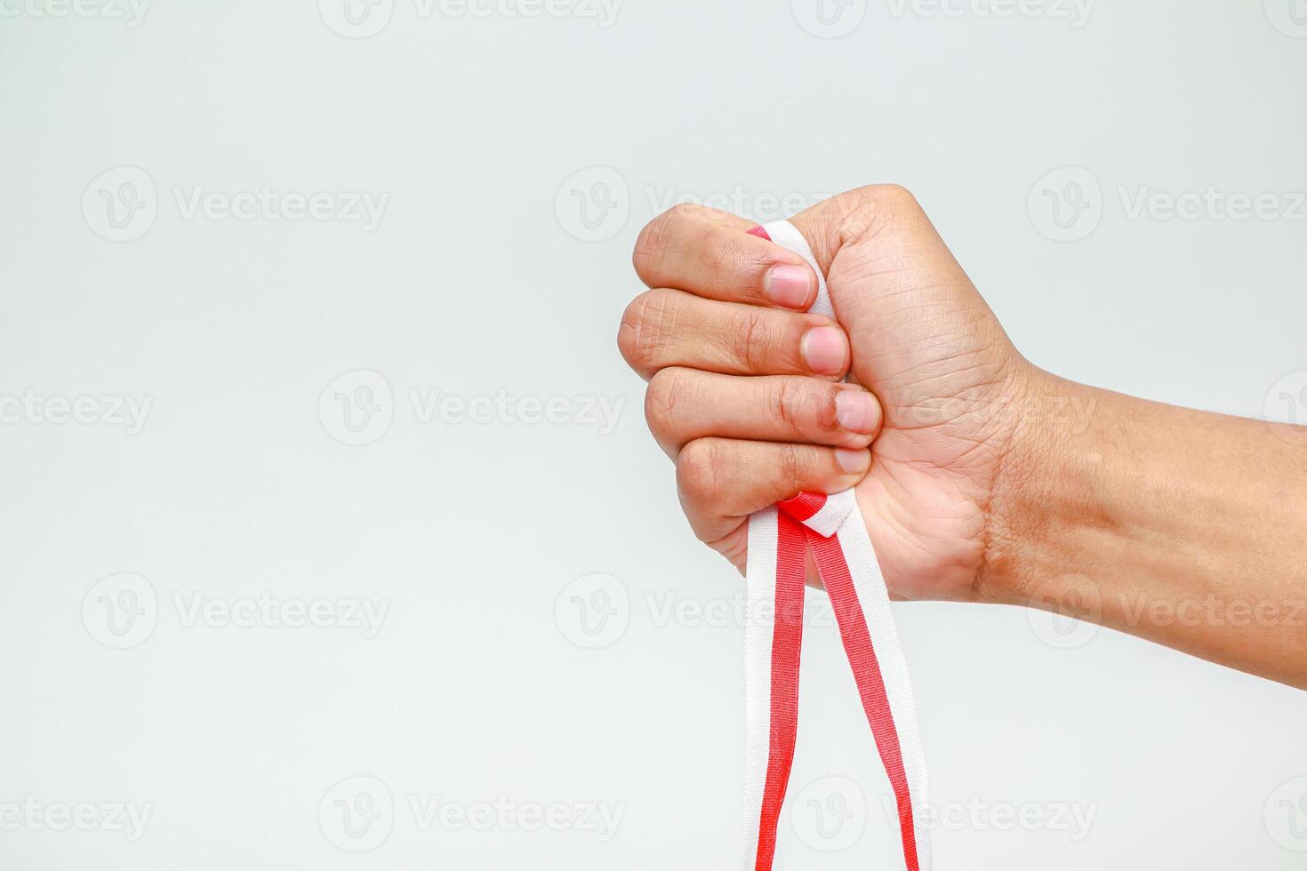 Hand gripping a red and white ribbon, symbolizing strength and national pride, isolated on white photo