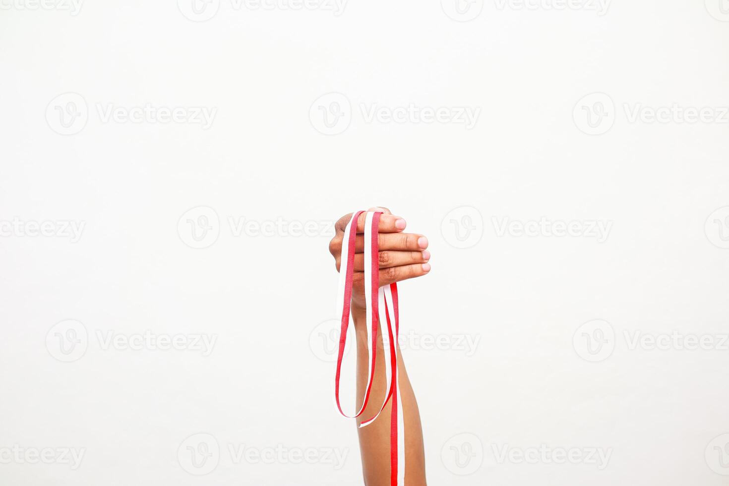 A hand holding red and white ribbons against a bright white background. Celebratory spirit photo