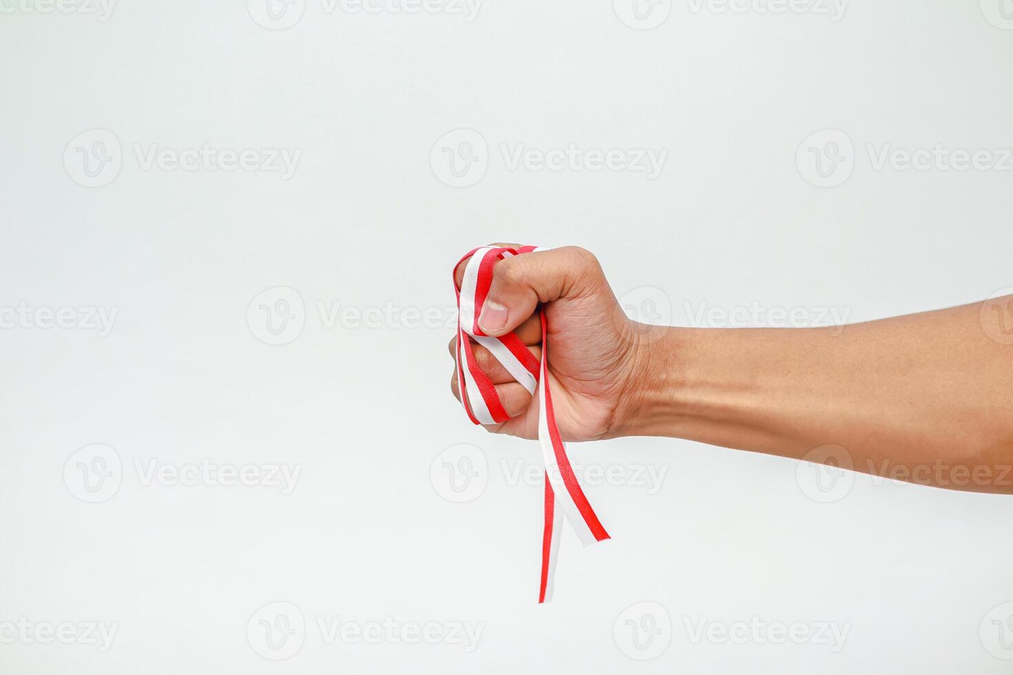 A fist clenching red and white ribbon, symbolizing Indonesia's strength and national pride on a clean, white background photo
