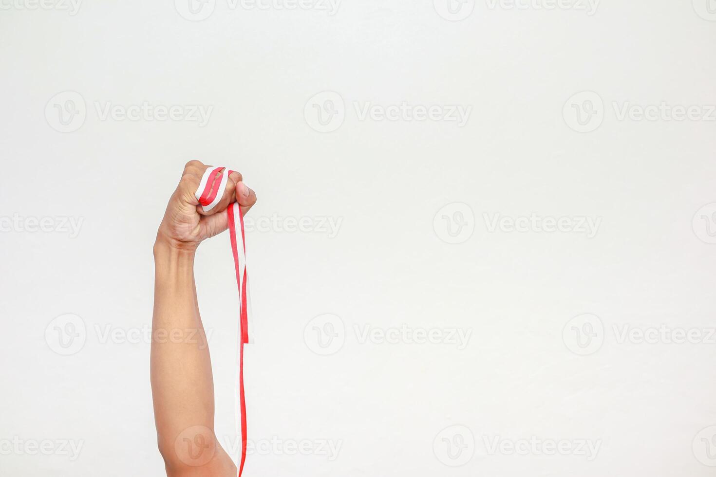 Hand holding a red and white ribbon in a fist symbolizing Indonesian Independence Day photo