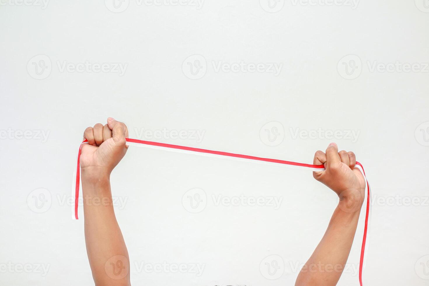 Hands holding and stretching a thin red ribbon against a plain white background, studio shot for physical activity and healthy lifestyle photo