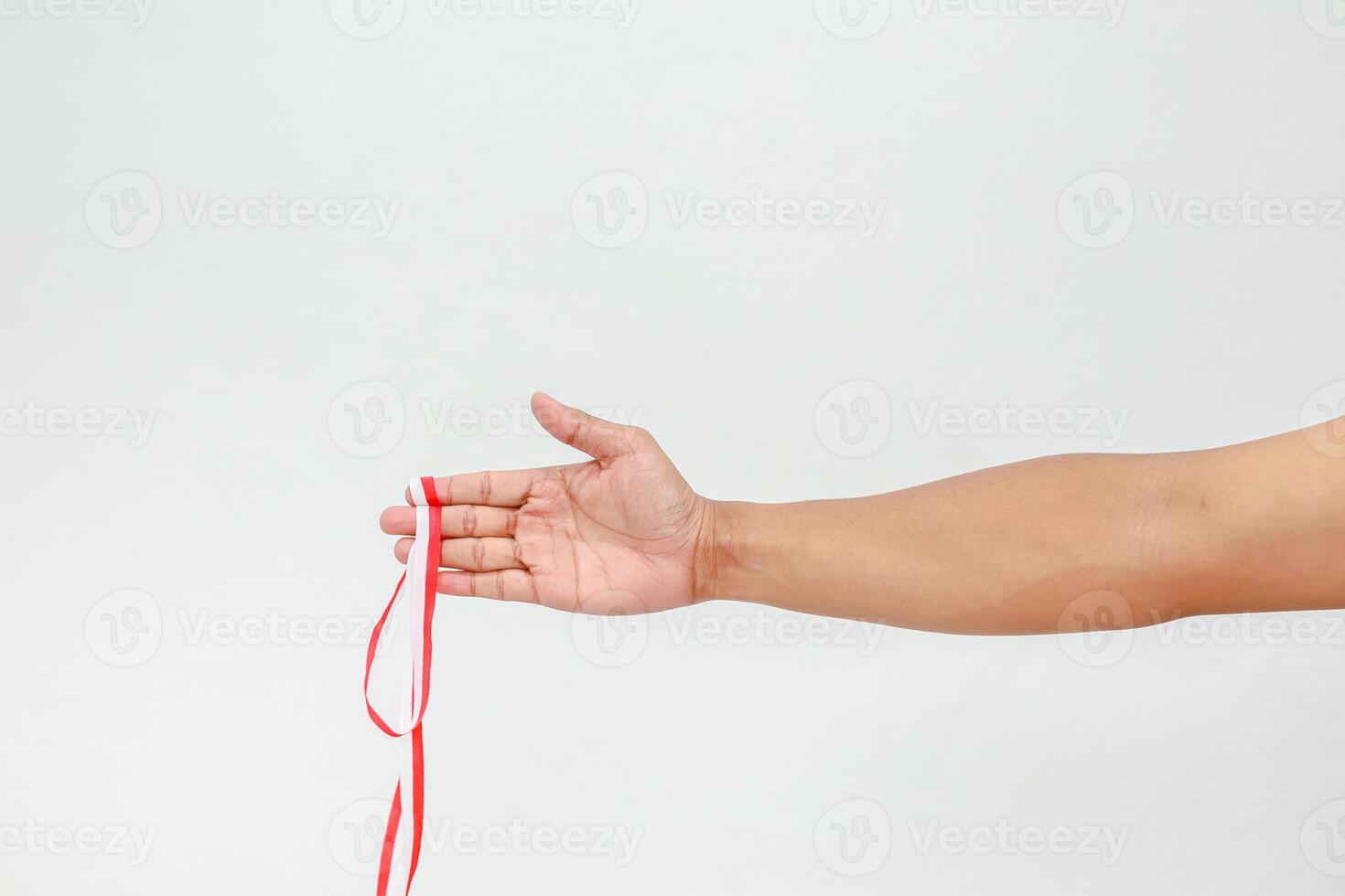 Isolated image featuring a person's arm and hand holding a red and white ribbon delicately photo