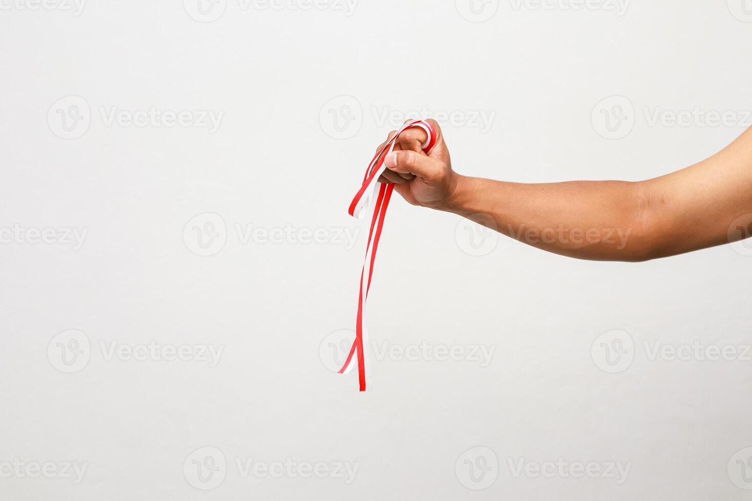 An Indonesian arm gripping a red and white ribbon celebrating independence day photo