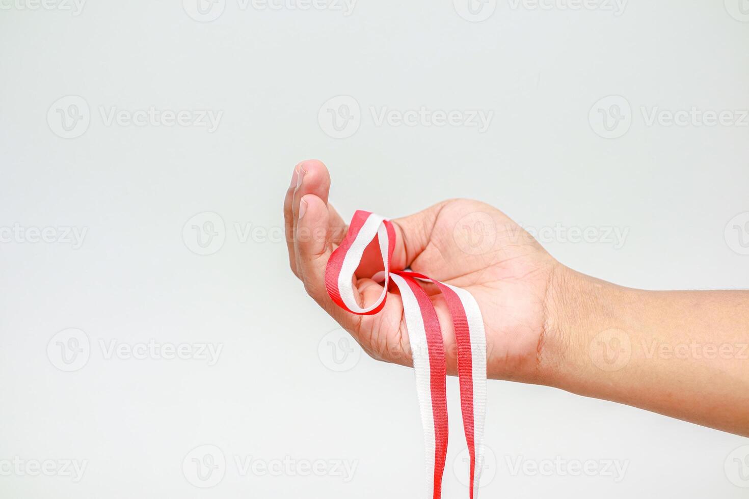 Hand holding Indonesian flag ribbon celebrating Independence Day, symbolizing freedom and patriotism photo