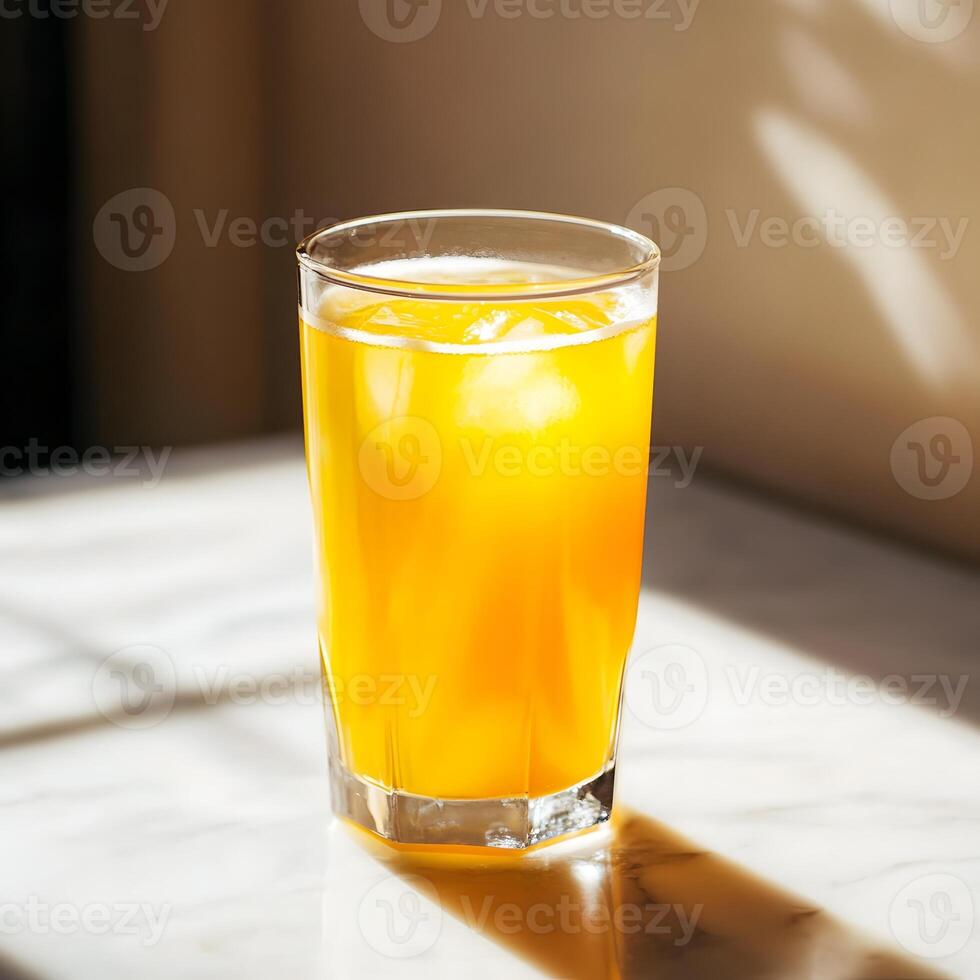 Orange juice in a glass on a white marble table with hard shadows. photo