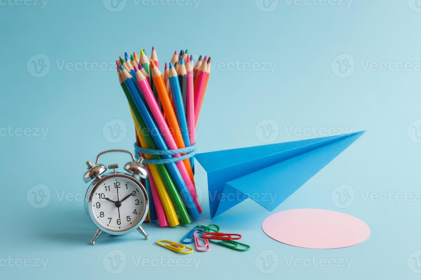 Back to school themed still life with colorful pencils a paper airplane and a clock signifying the importance of time management and learning photo