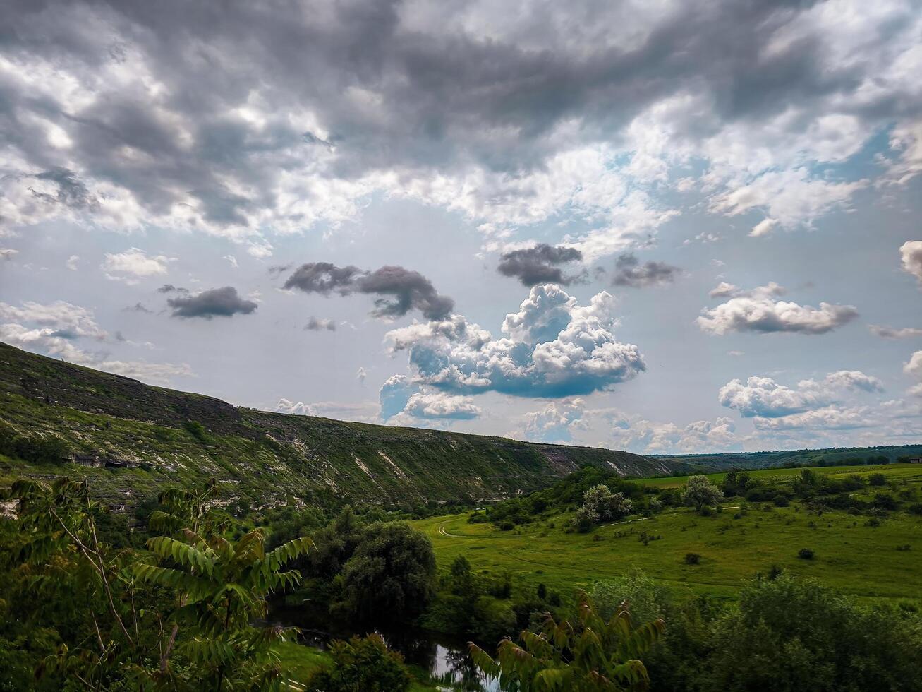 A cloudy sky with a hill in the background. The sky is overcast and the hill is covered in trees photo