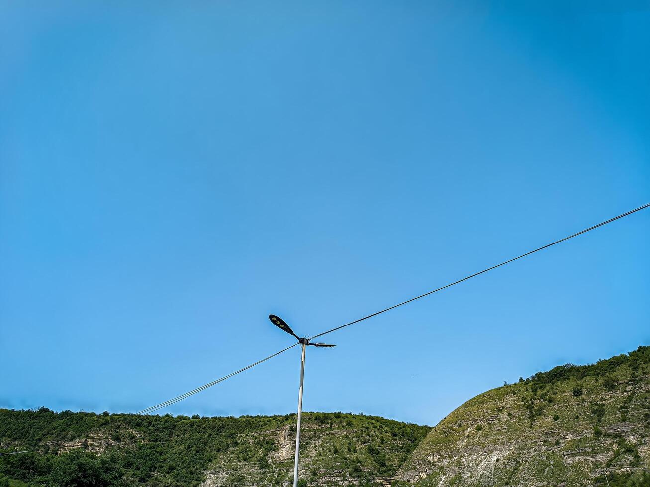 A tall pole with a light on top of it is standing in a field. The sky is clear and blue, and there are no clouds in sight. The scene is peaceful and serene photo