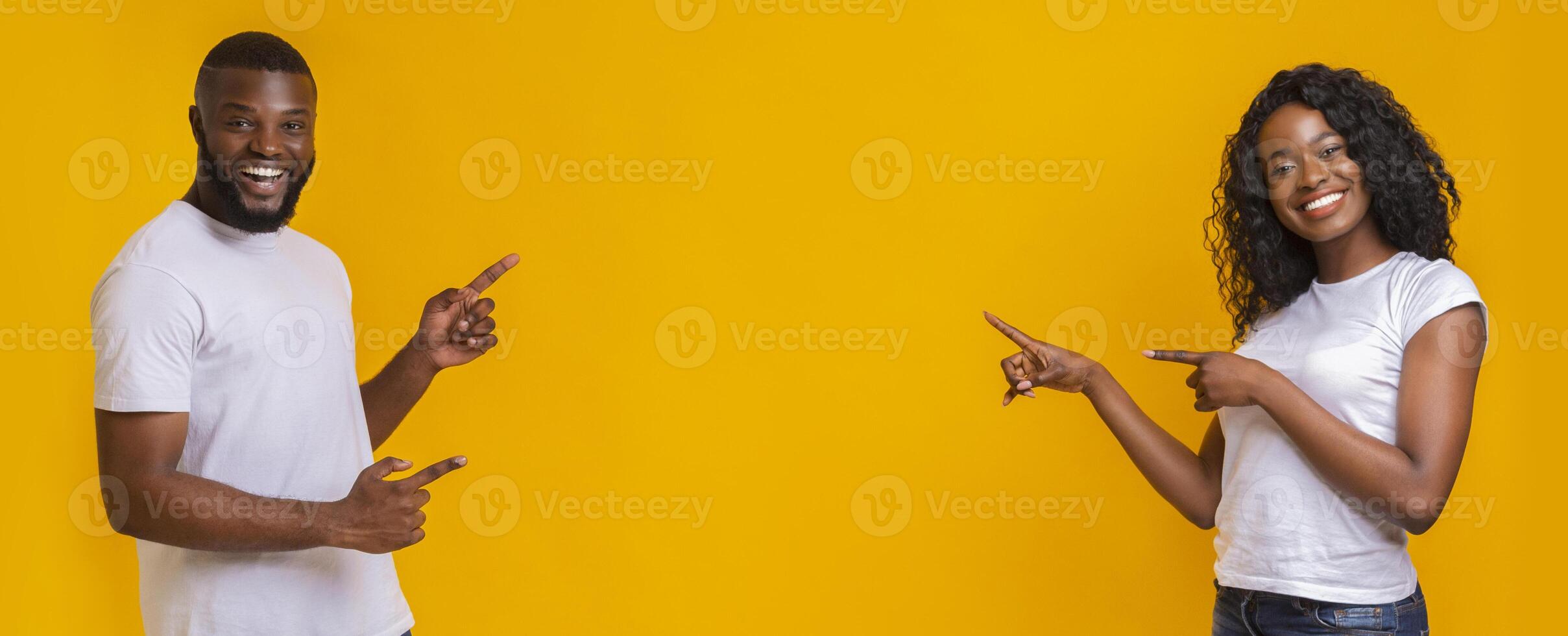 Lovely african couple pointing at copy space over yellow background, panorama photo