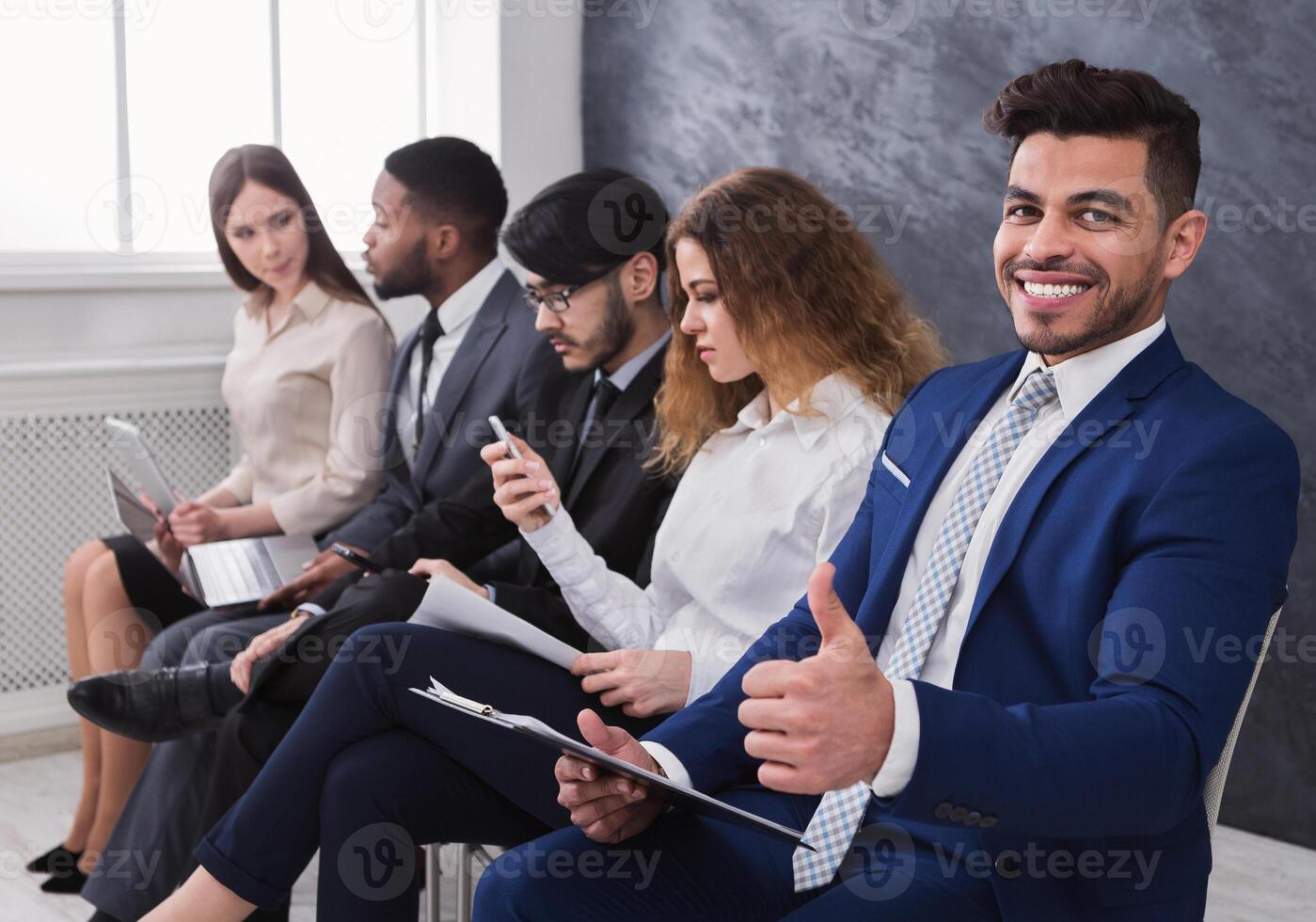 Cheerful man showing thumb up while waiting for interview in queue photo