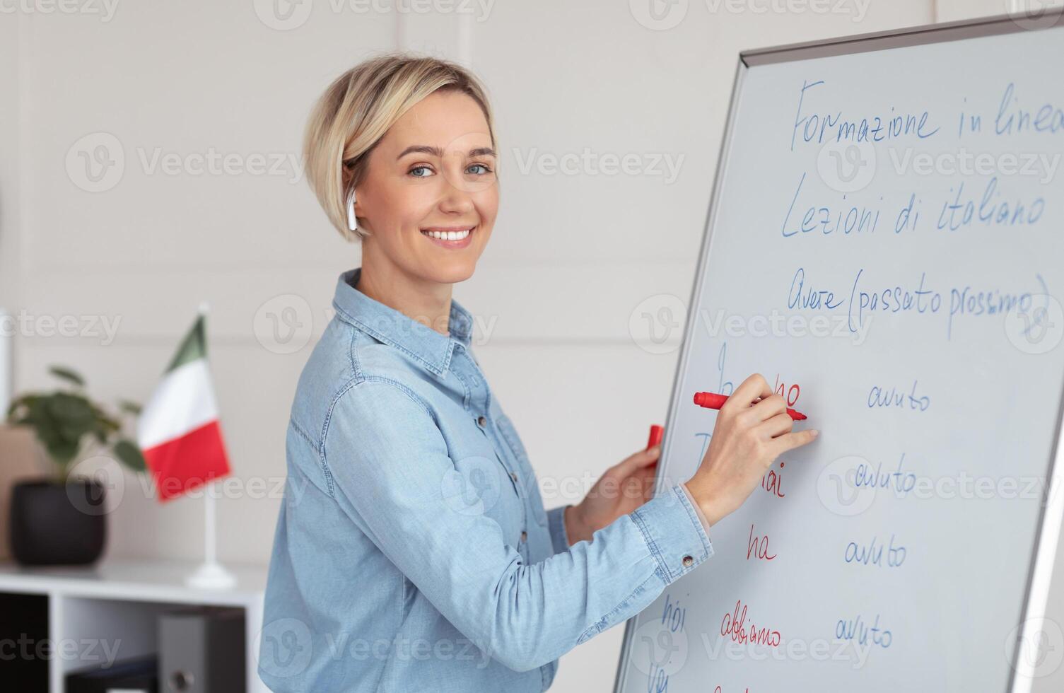 Online foreign languages school. Positive female teacher writing on blackboard, teaching Italian on web, explaining grammar rules to students. Happy young tutor giving lecture on internet photo