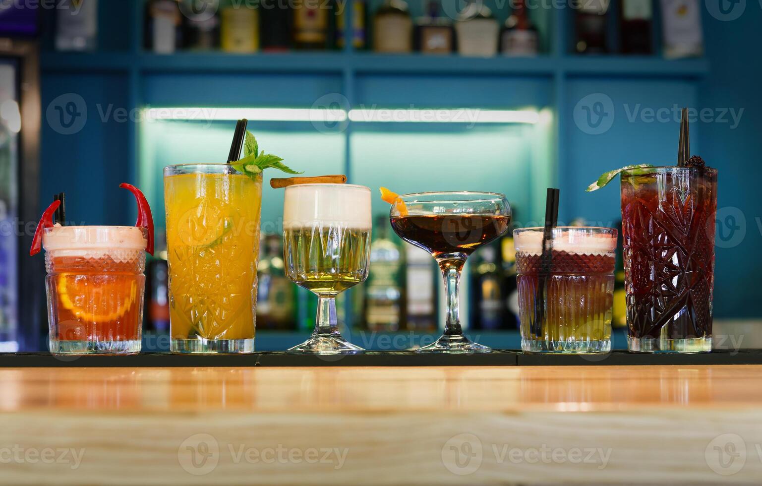 Closeup row of creative sweet exotic alcohol party cocktails in restaurant at bar background. Glasses with beverages on bar table, refreshing drinks with straws, night life concept photo