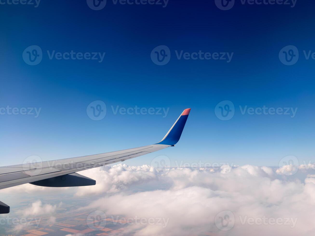 Airplane wing over cloudy landscape under clear blue sky at high altitude photo