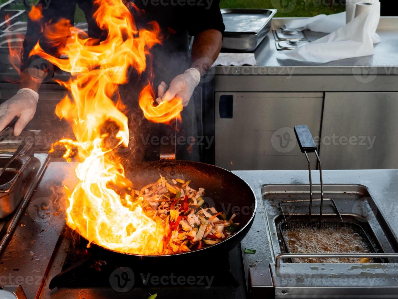 Chef cooking stir fry with flames outdoors in professional kitchen photo