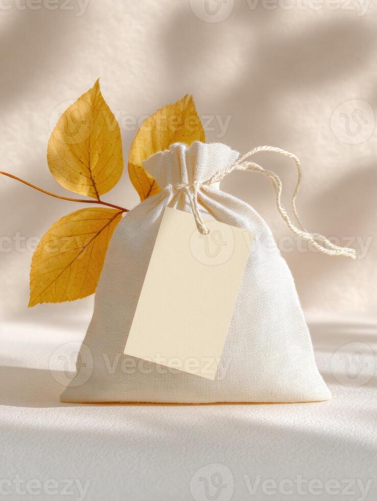 Elegant pastel product tag mockup on cotton drawstring pouch with autumn leaves photo