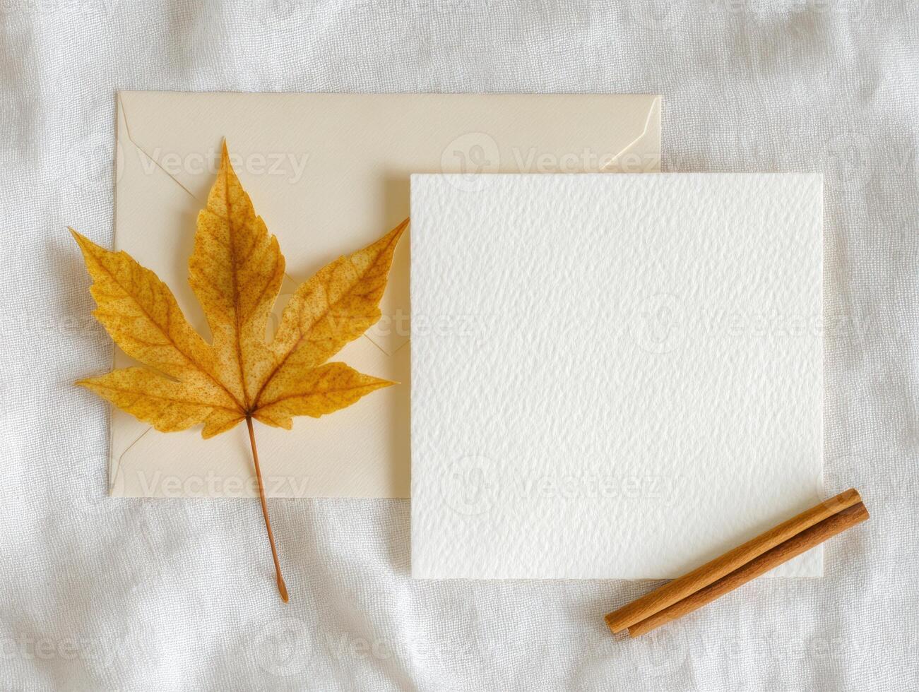 Autumn theme flat lay with square card, envelope, maple leaf, and cinnamon sticks photo