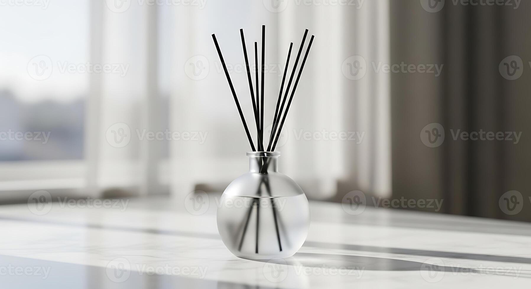 A vase with reed sticks on a table in front of a window photo