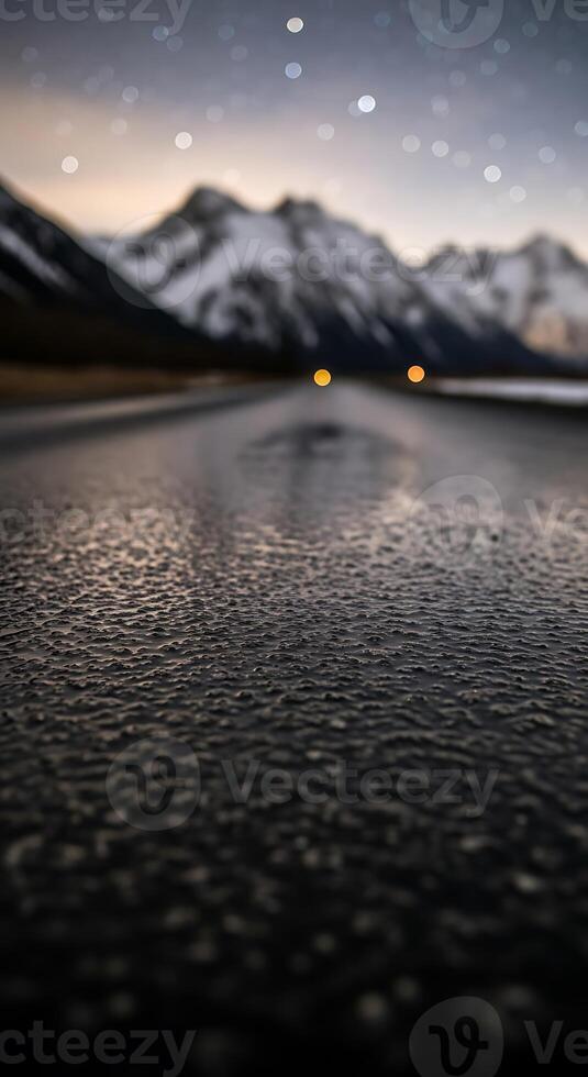 A dark road leading to snow covered mountains under a night sky photo