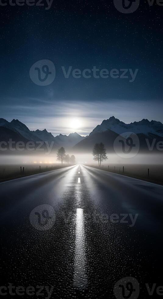 A long road leading to mountains under a starry sky with fog and moonlight creating a serene landscape photo