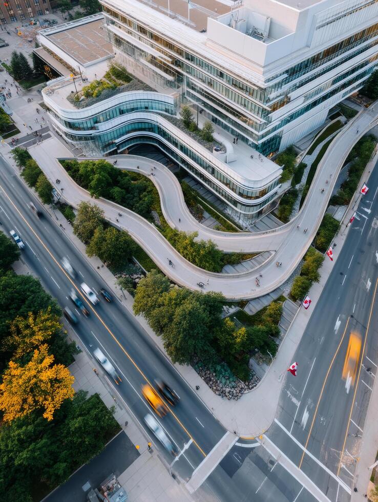 Aerial view of modern building with curved architecture, surrounded by greenery and busy streets photo