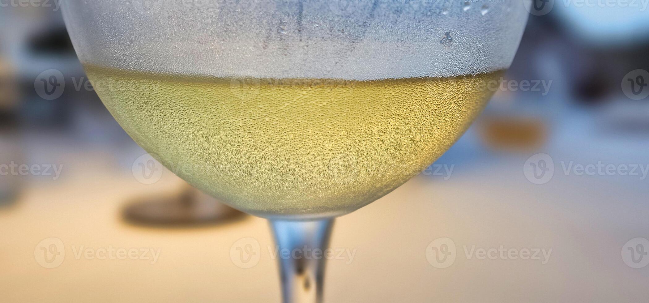 A glass of chilled white wine against a blurred background in a restaurant on the Ligurian Riviera in the summer of 2025. photo