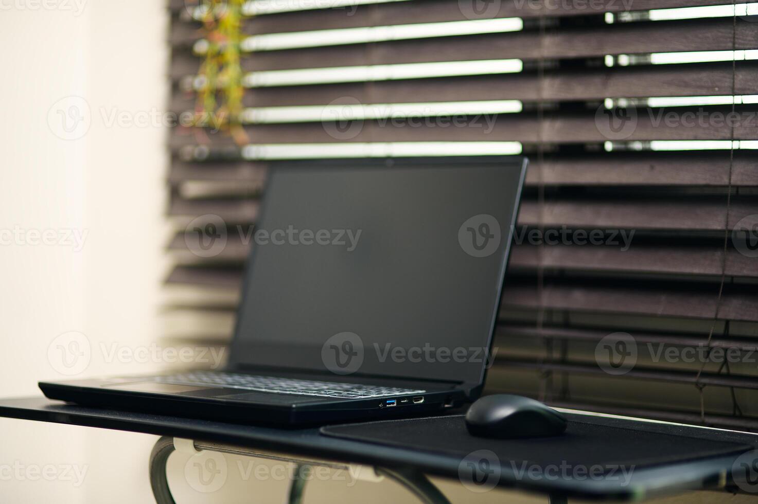 Sleek Laptop and Mouse on Minimalist Desk with Blinds in Background photo