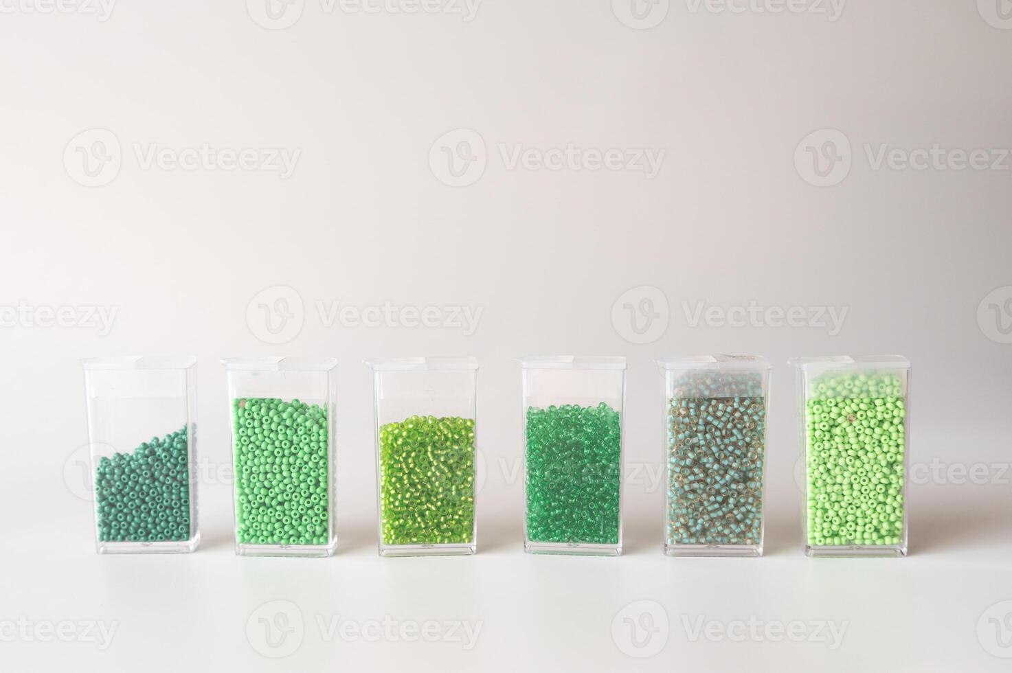 Set of transparent containers with green beads in gradients on white background photo