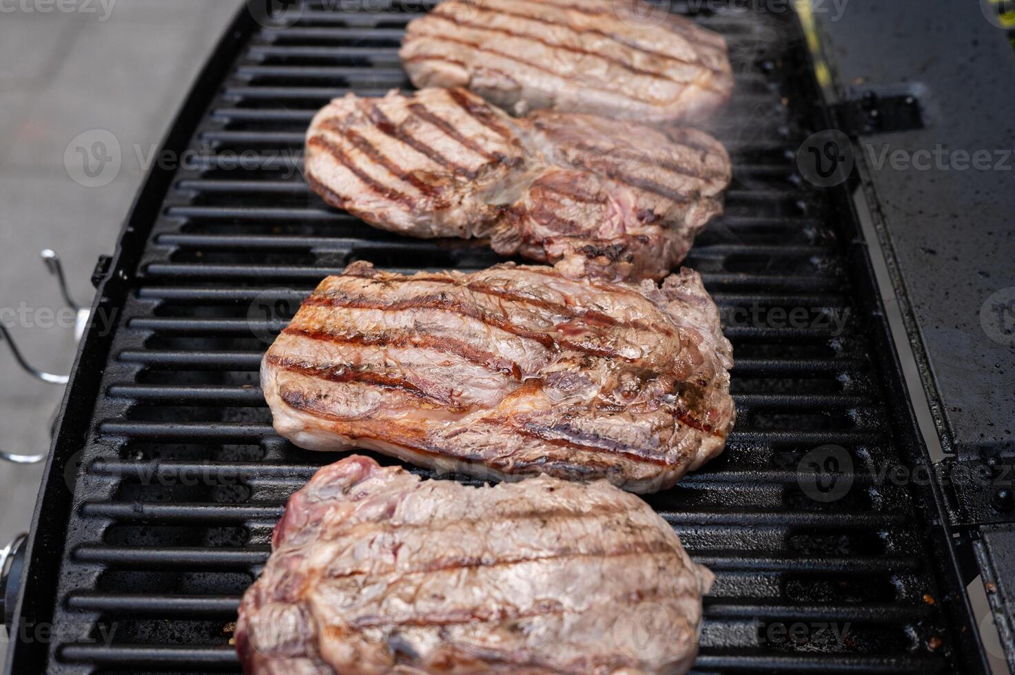 Juicy steaks grilling on outdoor bbq with smoky aroma photo