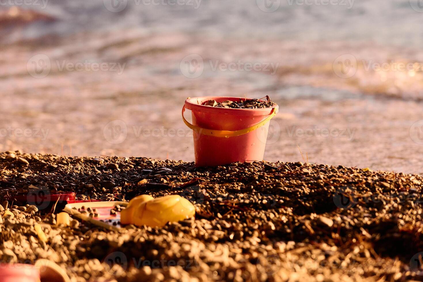 Toy bucket and tools on beach at sunset photo