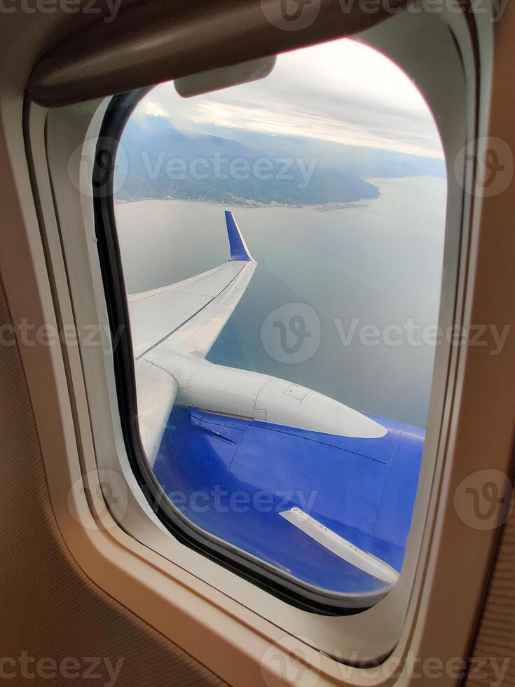 beautiful thick clouds in the sky from the height of the flight of the plane with a view of the wing with engines through the round window photo