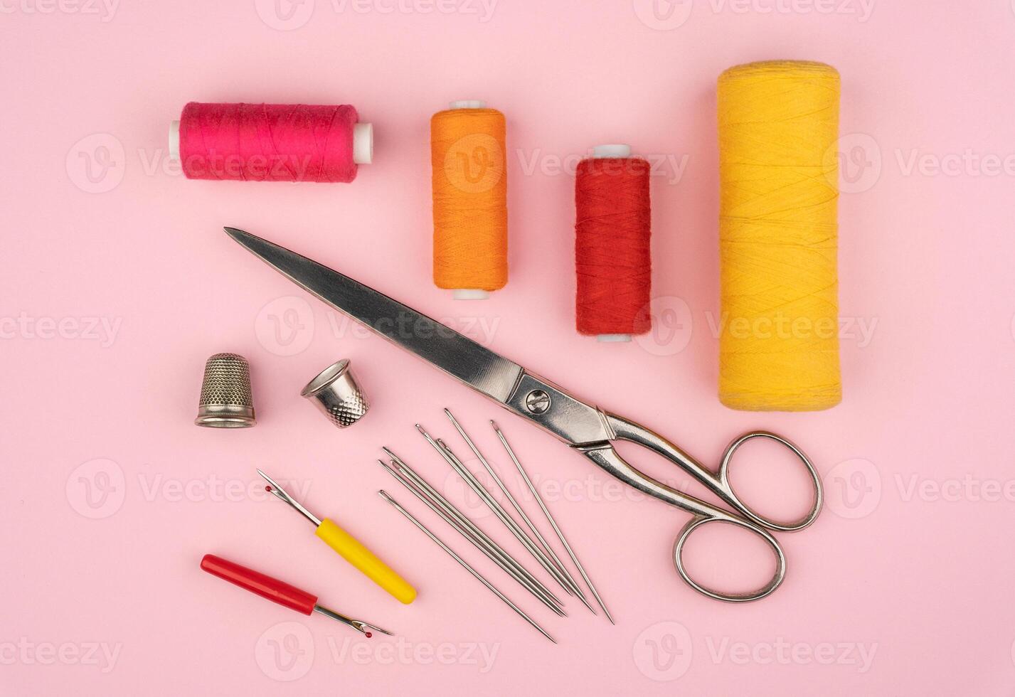 various tailor accessories and tools for tailoring on pink background photo
