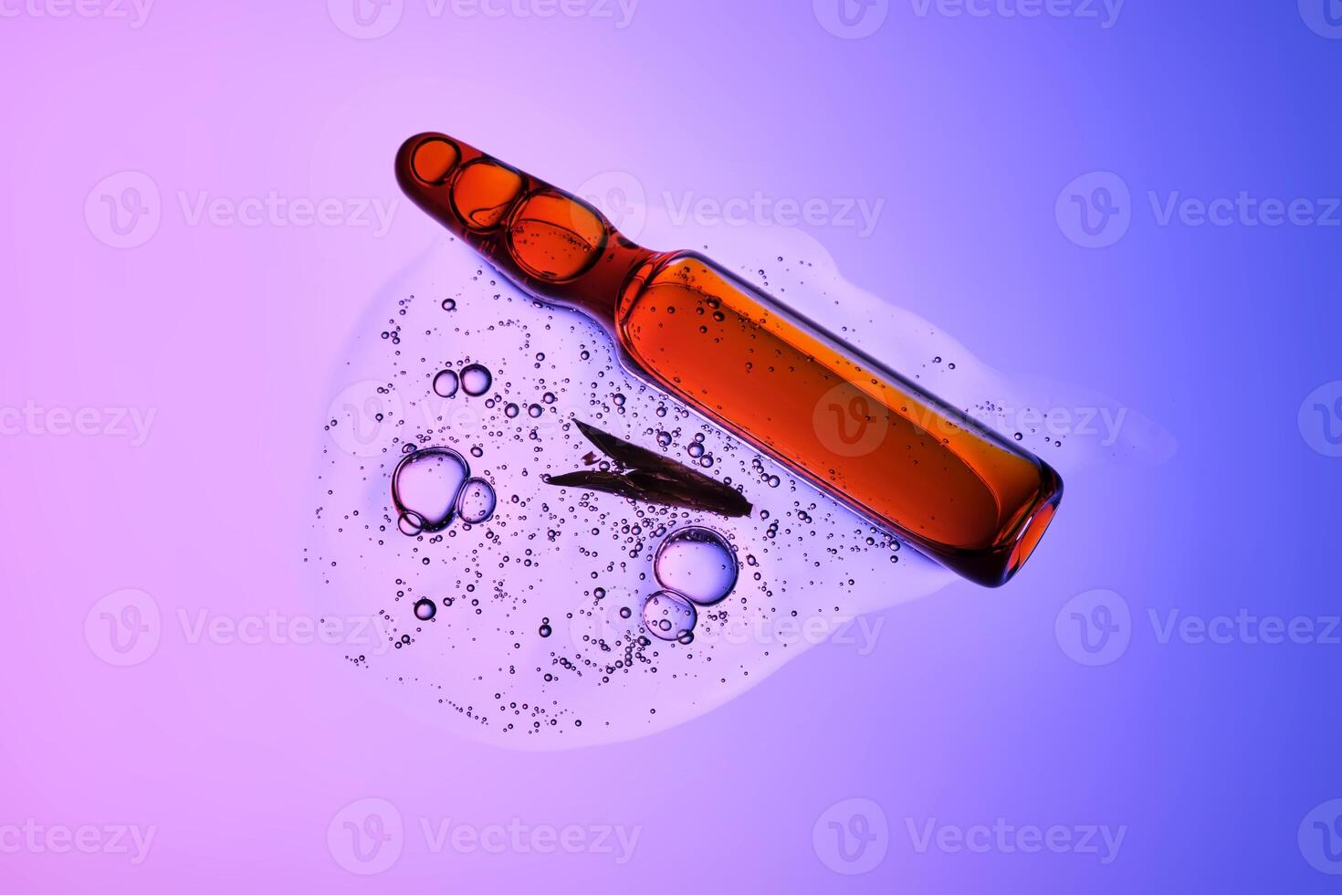 An ampoule with serum in its texture on a purple background with a leaf. photo