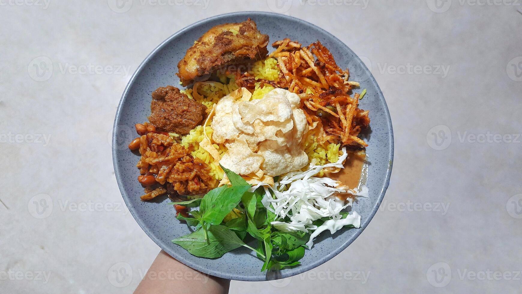 Nasi kuning or Yellow Rice is Indonesian Food Served With Chicken and Various Side Dishes On a Plate photo