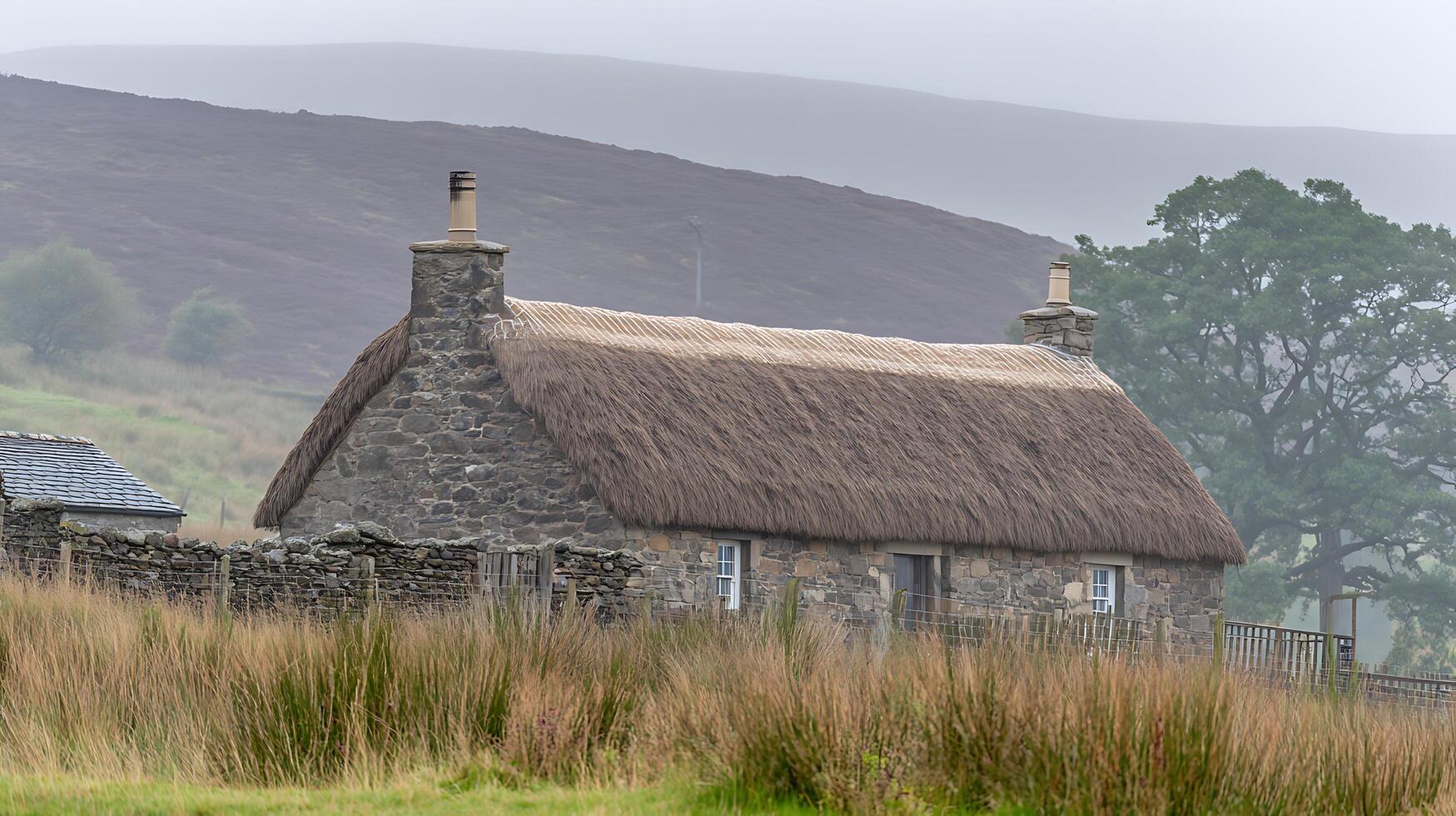 Old Stone Cottage with Thatched Roof in Misty Scottish Highlands. photo