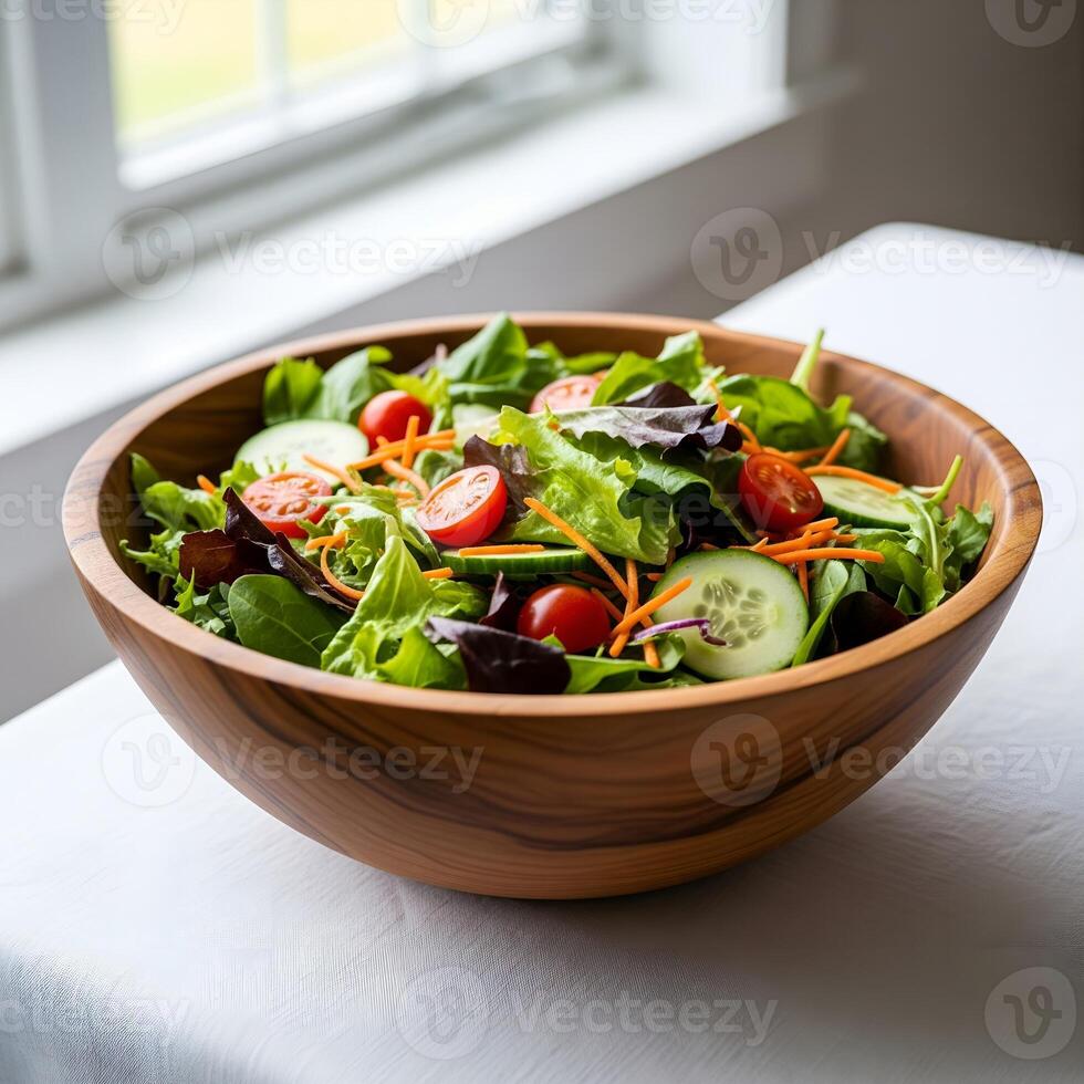 A bowl of fresh vegetable salad in a wooden bowl near a bright window photo