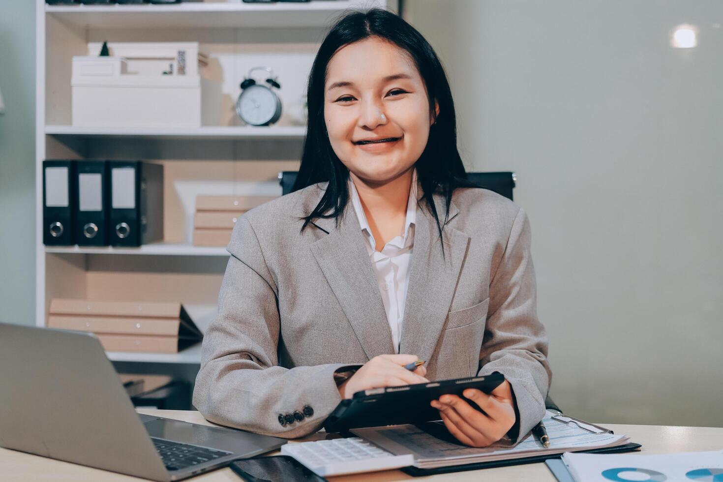 Asian business woman smiling while working at desk photo