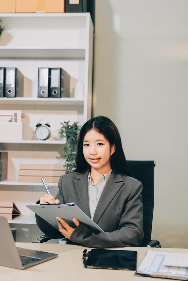 Asian business woman in office with laptop and pen photo