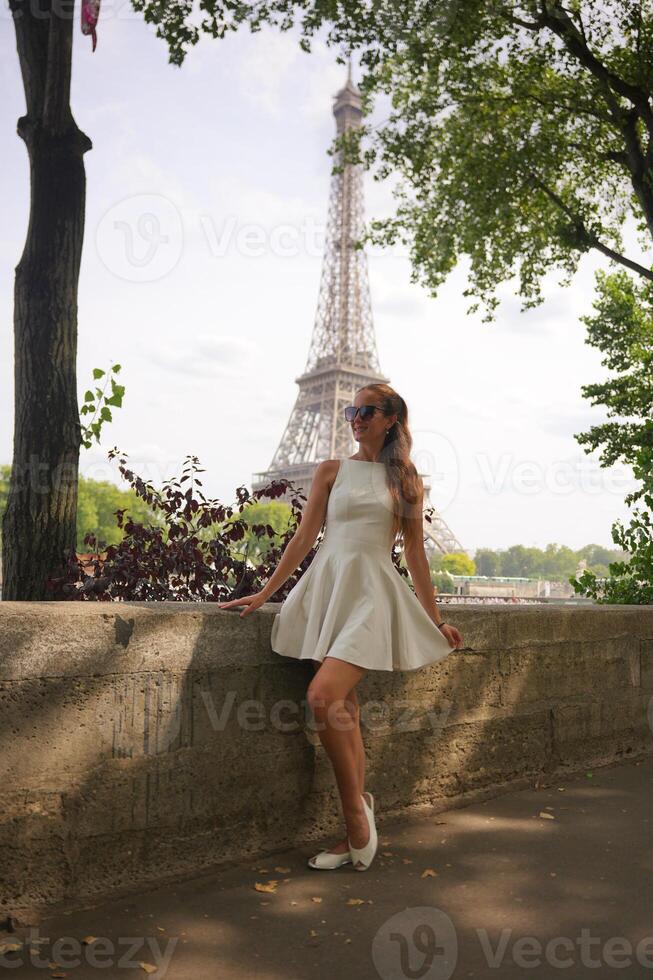 Woman in white dress posing near Eiffel Tower in summer Paris photo