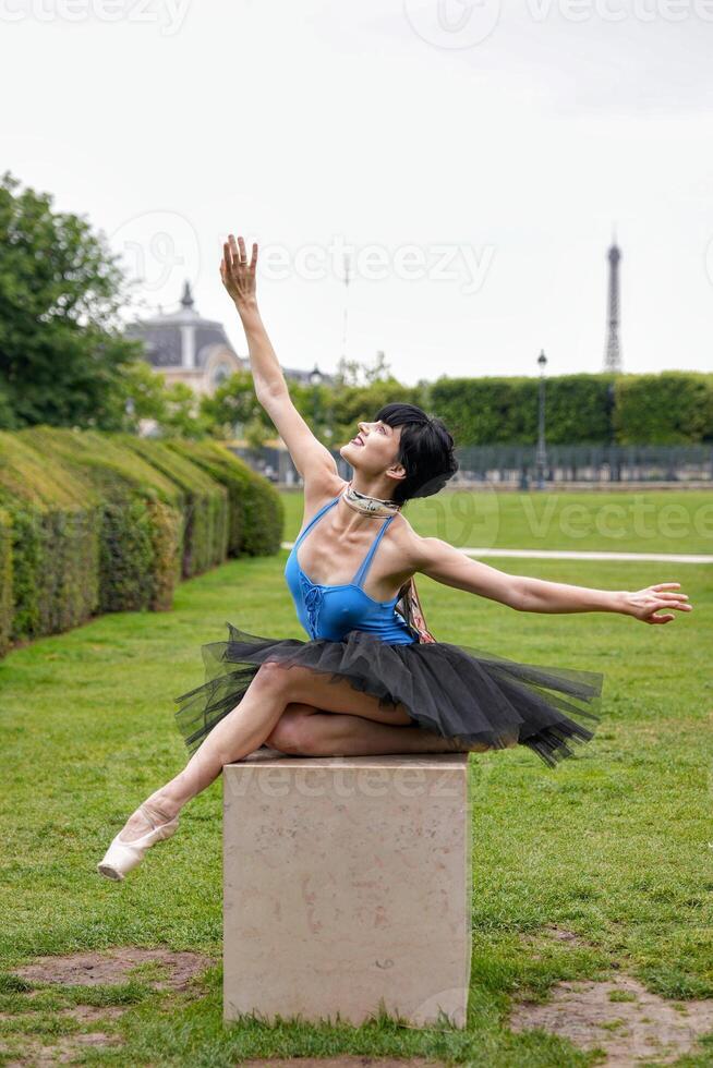 Ballet dancer stretching arms in elegant pose on garden pedestal photo