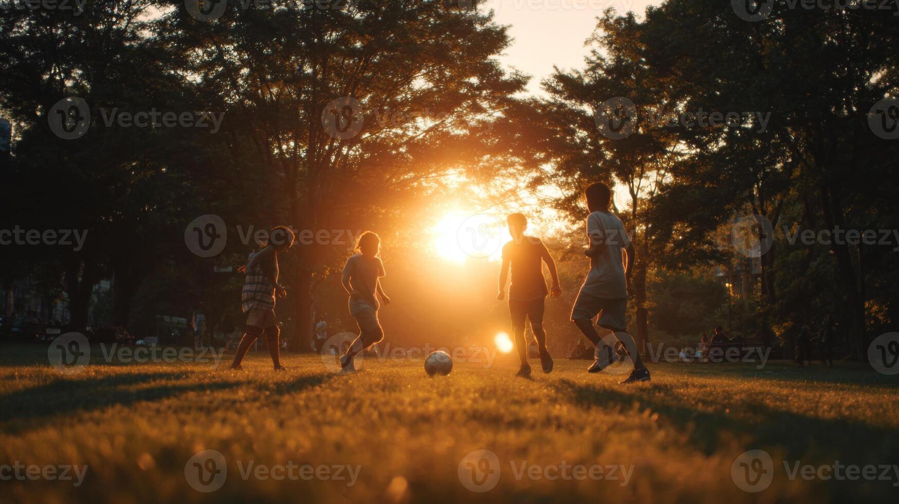 Joyful children playing soccer at sunset in a park with warm orange sunlight illuminating the scene and creating playful shadows photo