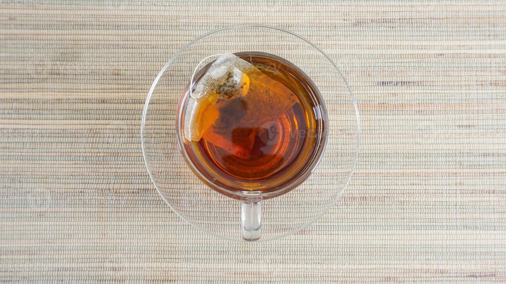 Top view of a cup of tea with teabag isolated on wooden texture background photo