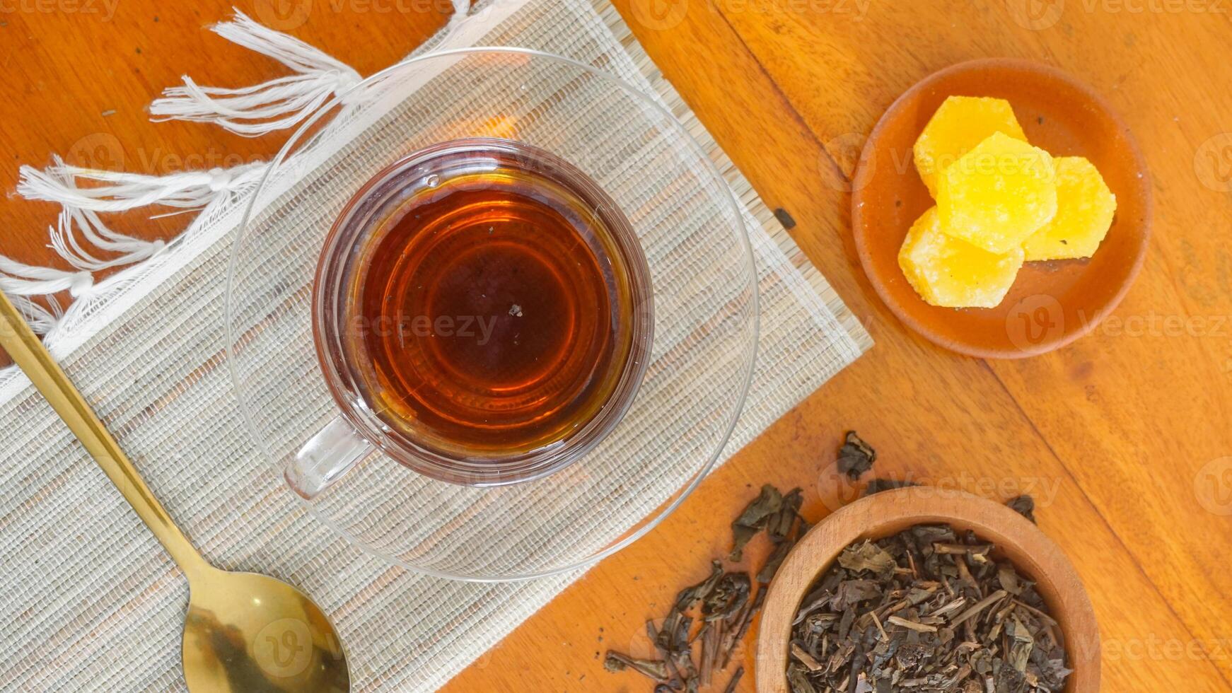 Top view of a cup of tea with sugar cubes and ground tea leaves isolated on wooden texture background photo