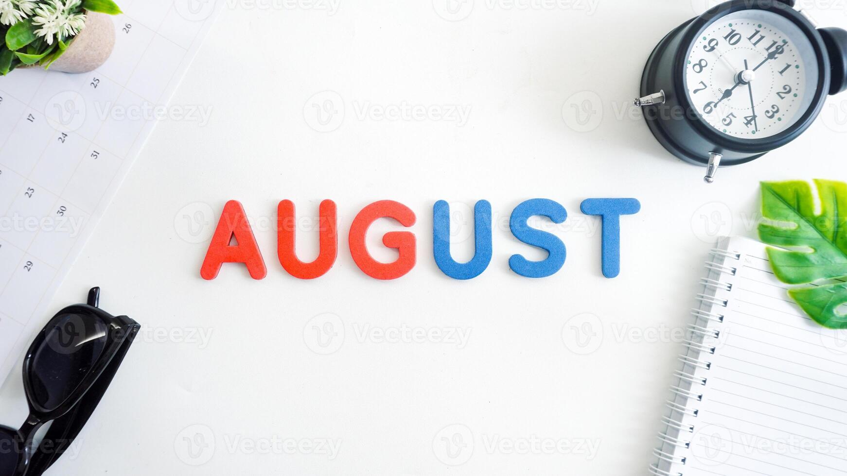 Flat lay composition with red and blue color foam letters spelling word AUGUST isolated on white background photo